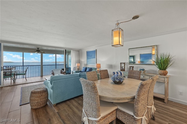 dining space featuring floor to ceiling windows, dark hardwood / wood-style floors, ceiling fan, and a water view