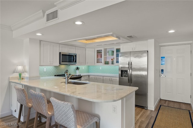 kitchen with white cabinetry, stainless steel appliances, kitchen peninsula, and a breakfast bar area