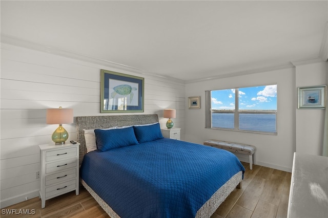 bedroom with a water view, ornamental molding, and wood-type flooring