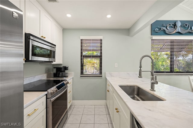 kitchen with sink, light stone counters, light tile patterned floors, appliances with stainless steel finishes, and white cabinets