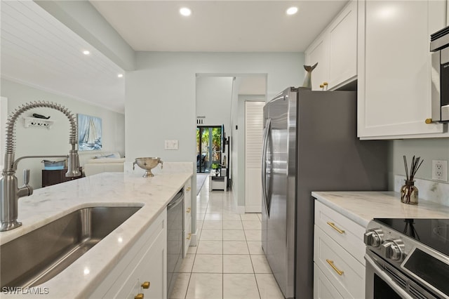 kitchen with light tile patterned flooring, appliances with stainless steel finishes, sink, white cabinets, and light stone counters