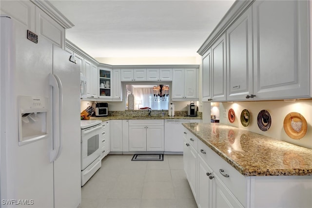 kitchen with light stone countertops, white cabinets, and white appliances