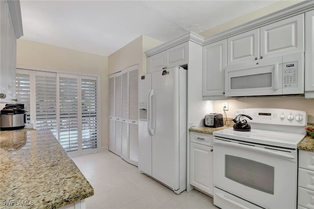 kitchen featuring light stone counters, white appliances, white cabinets, and light tile patterned flooring