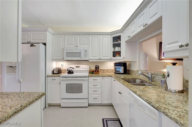 kitchen with sink, white cabinetry, light tile patterned floors, white appliances, and light stone countertops