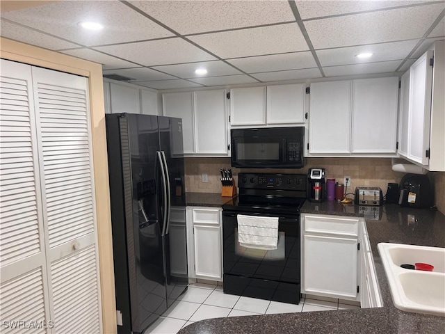 kitchen featuring sink, white cabinetry, black appliances, light tile patterned floors, and backsplash