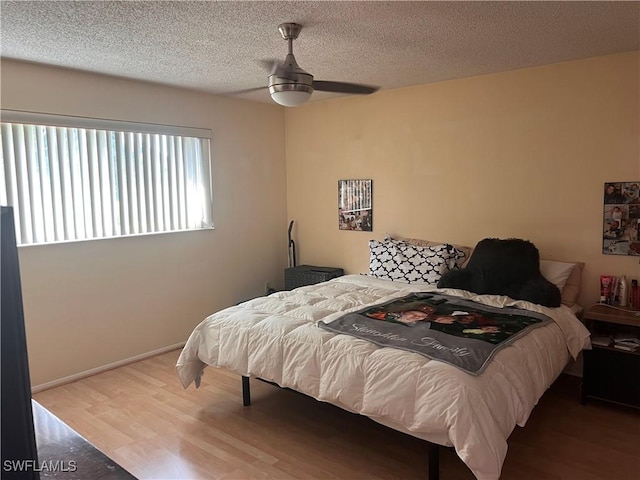 bedroom with ceiling fan, wood-type flooring, and a textured ceiling