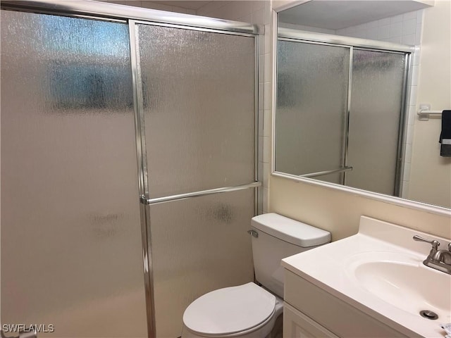 bathroom with toilet, vanity, and a shower with shower door