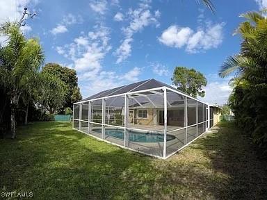 view of swimming pool with a yard and a lanai