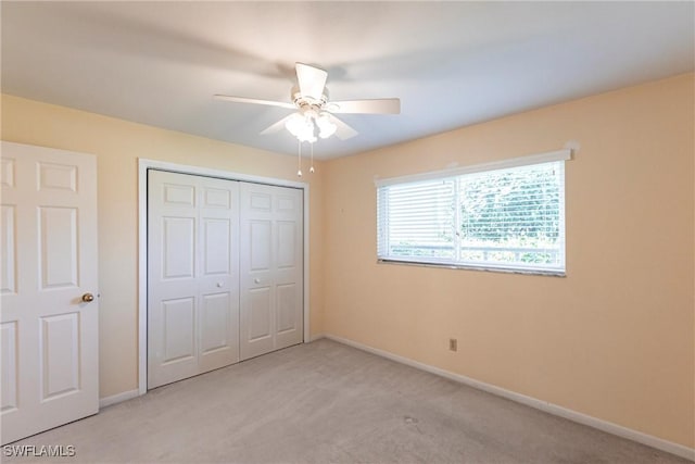 unfurnished bedroom with light colored carpet, ceiling fan, and a closet