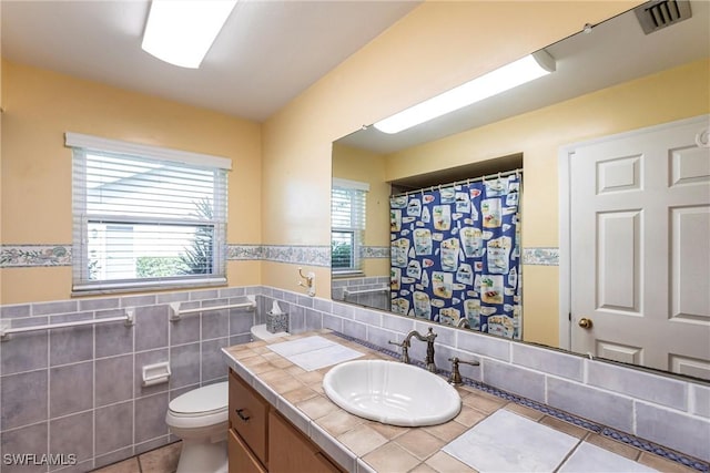 bathroom with tile patterned floors, vanity, toilet, and tile walls