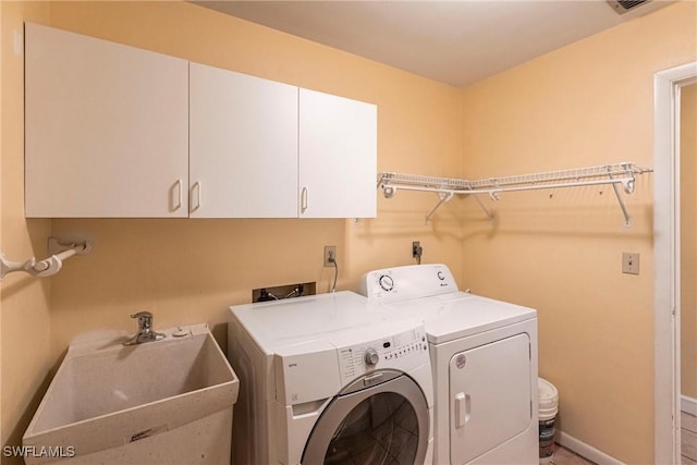 clothes washing area with cabinets, sink, and washer and clothes dryer