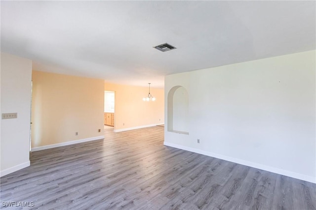 spare room featuring wood-type flooring and a notable chandelier