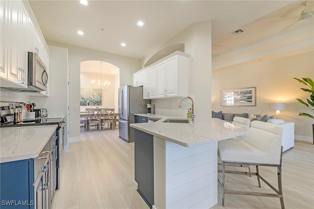 kitchen featuring arched walkways, a sink, visible vents, appliances with stainless steel finishes, and a kitchen bar