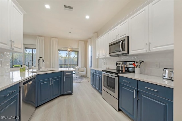 kitchen with stainless steel appliances, visible vents, a sink, and blue cabinetry