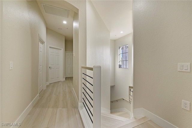 interior space featuring light wood-type flooring, recessed lighting, baseboards, and an upstairs landing