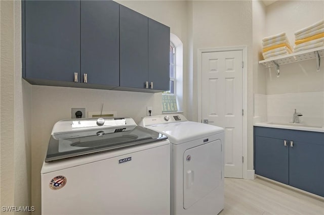 laundry area with light wood finished floors, independent washer and dryer, a sink, and cabinet space