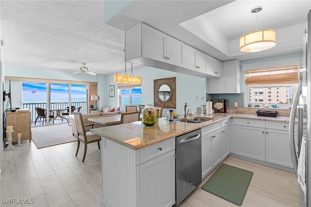 kitchen featuring stainless steel appliances, decorative light fixtures, kitchen peninsula, and white cabinets