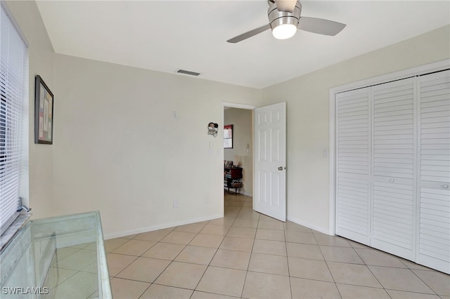 unfurnished bedroom featuring ceiling fan, a closet, and light tile patterned floors