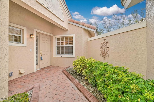 property entrance with a tiled roof and stucco siding