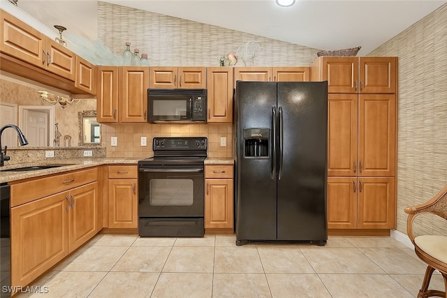 20037 Serene Meadow Ln, Estero, FL 33928 - kitchen with black appliances, vaulted ceiling, wallpapered walls, light tile patterned floors, and light stone countertops