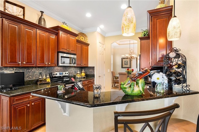 kitchen with pendant lighting, appliances with stainless steel finishes, a breakfast bar area, and dark stone counters