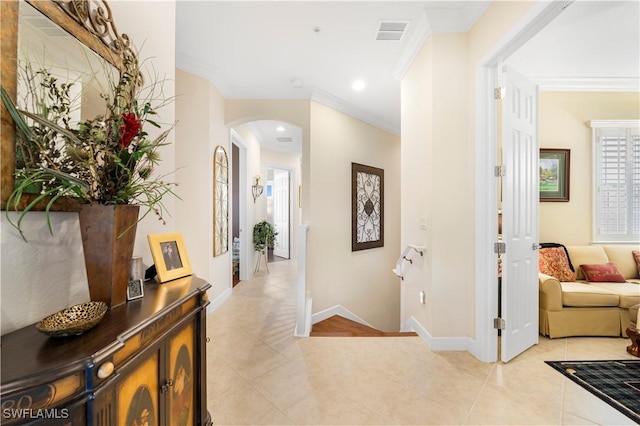 hall with ornamental molding and light tile patterned floors