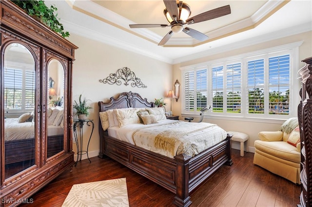 bedroom with multiple windows, dark wood-type flooring, ornamental molding, and a raised ceiling