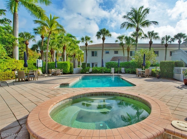 view of swimming pool featuring an in ground hot tub and a patio