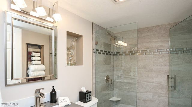 bathroom with sink, a shower with shower door, and toilet