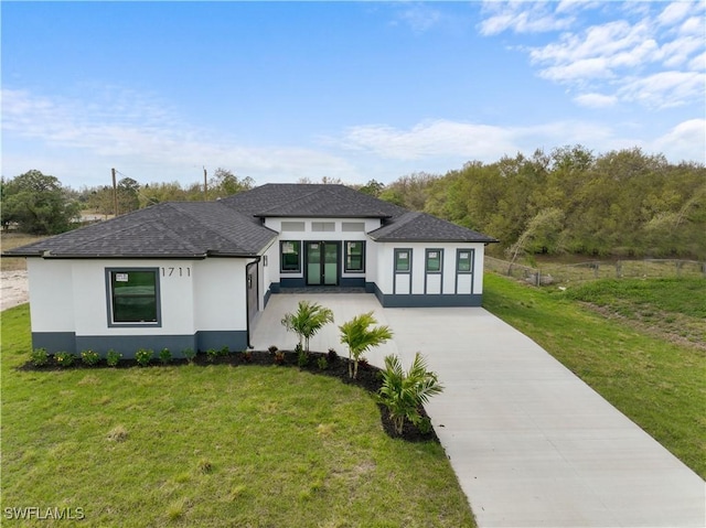 view of front of home with concrete driveway, a front lawn, a shingled roof, and stucco siding