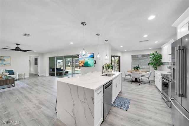 kitchen featuring stainless steel appliances, sink, a center island with sink, and white cabinets