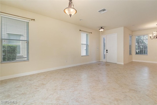 spare room with baseboards, visible vents, light tile patterned floors, and an inviting chandelier