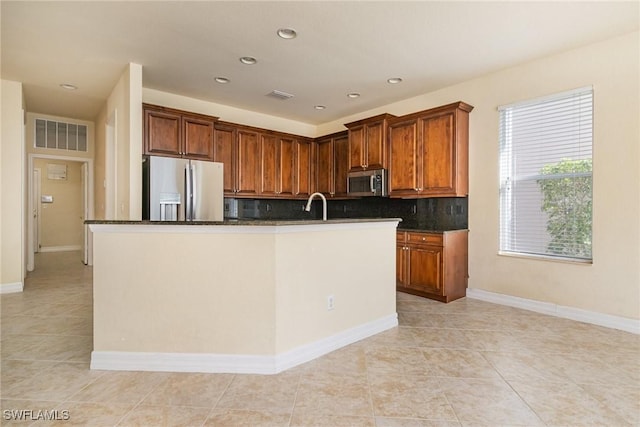 kitchen featuring light tile patterned flooring, an island with sink, stainless steel appliances, backsplash, and visible vents