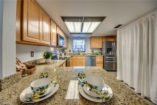 kitchen with kitchen peninsula, appliances with stainless steel finishes, and light stone countertops