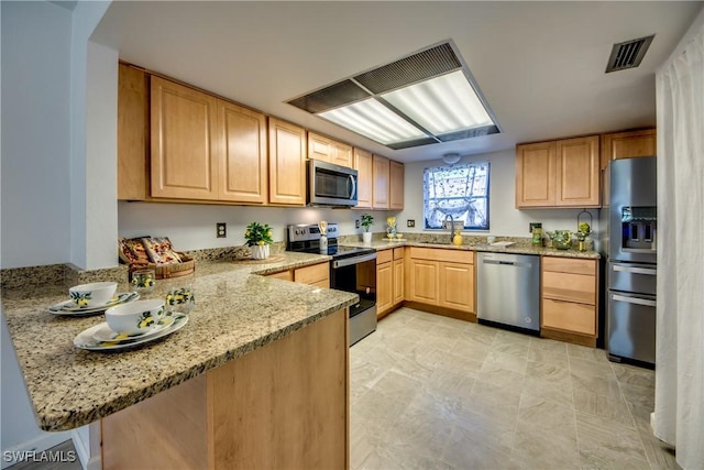 kitchen with light stone counters, stainless steel appliances, kitchen peninsula, and light brown cabinets