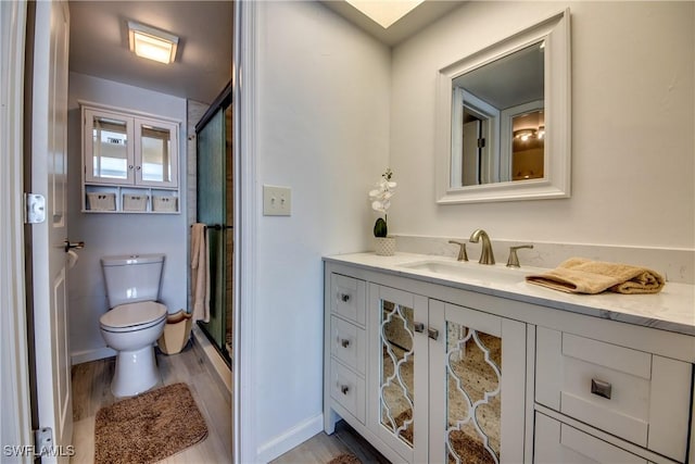 bathroom with wood-type flooring, vanity, an enclosed shower, and toilet