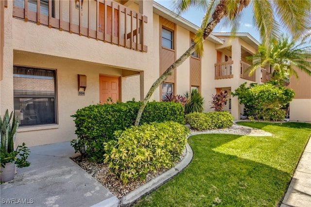 doorway to property featuring a lawn and a balcony