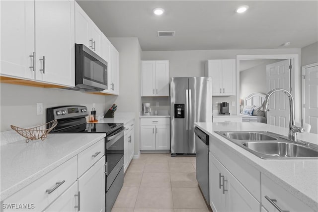 kitchen with white cabinetry, appliances with stainless steel finishes, light tile patterned flooring, and sink