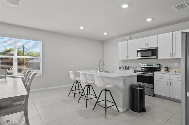 4320 Little Hickory Rd, Bonita Springs, FL 34134 - kitchen with stainless steel appliances, white cabinetry, a kitchen island with sink, and a kitchen bar