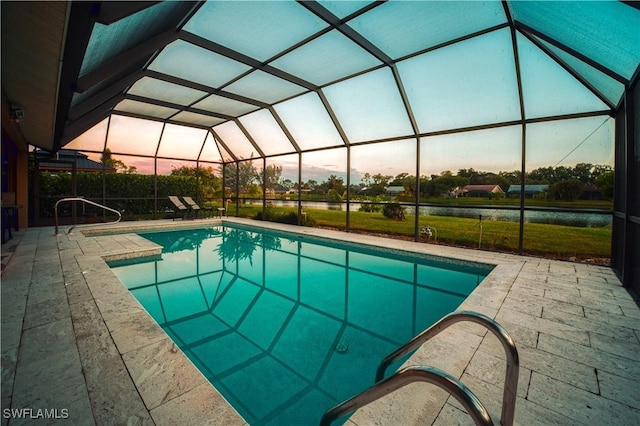 pool at dusk featuring a patio and glass enclosure