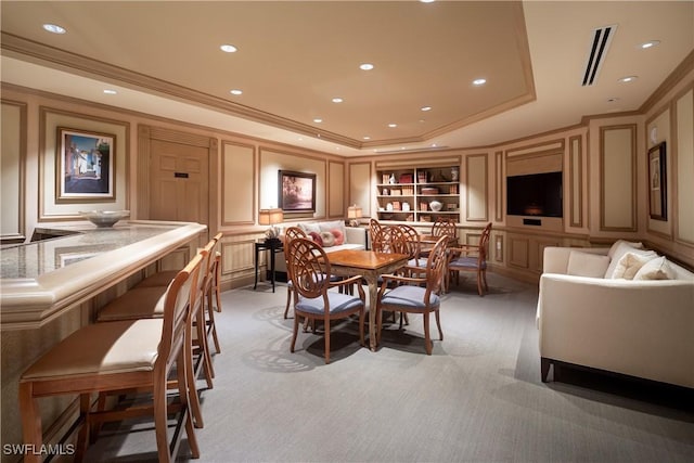 dining space with a tray ceiling, crown molding, built in features, and carpet