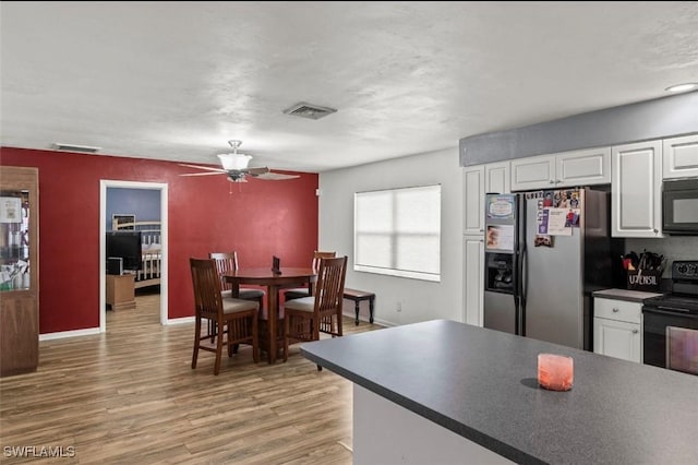 kitchen featuring hardwood / wood-style flooring, white cabinets, ceiling fan, and black appliances