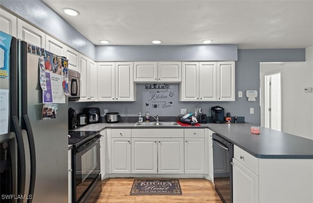 kitchen with sink, light hardwood / wood-style flooring, white cabinetry, black appliances, and kitchen peninsula