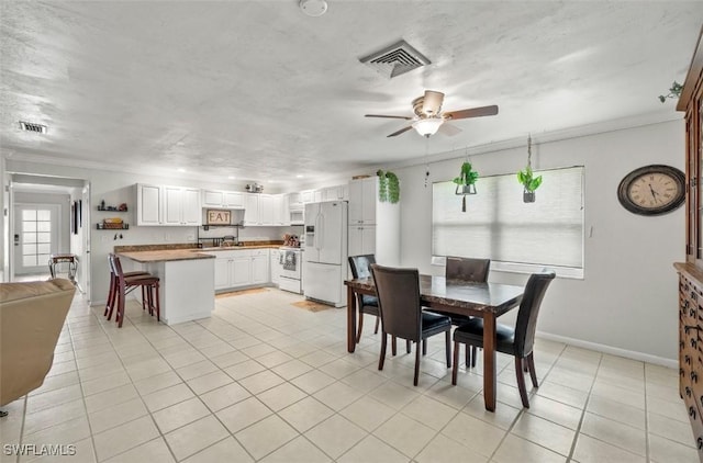 tiled dining space with crown molding, sink, a textured ceiling, and ceiling fan