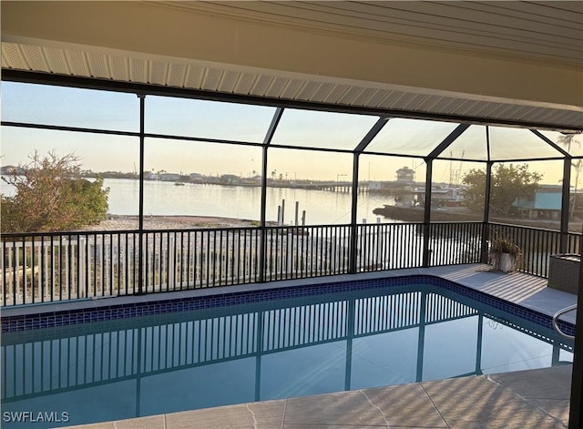 pool at dusk featuring a water view and glass enclosure