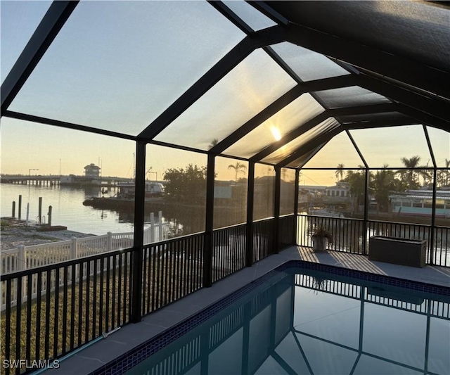 pool at dusk with a water view and a lanai