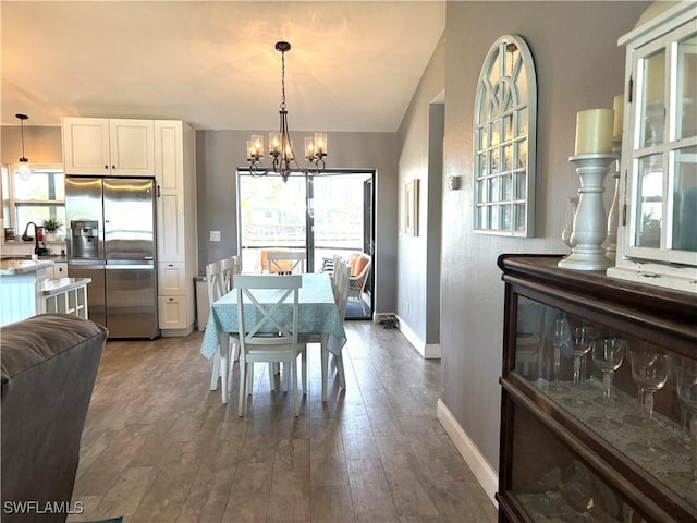 dining space featuring lofted ceiling, dark hardwood / wood-style flooring, a chandelier, and sink