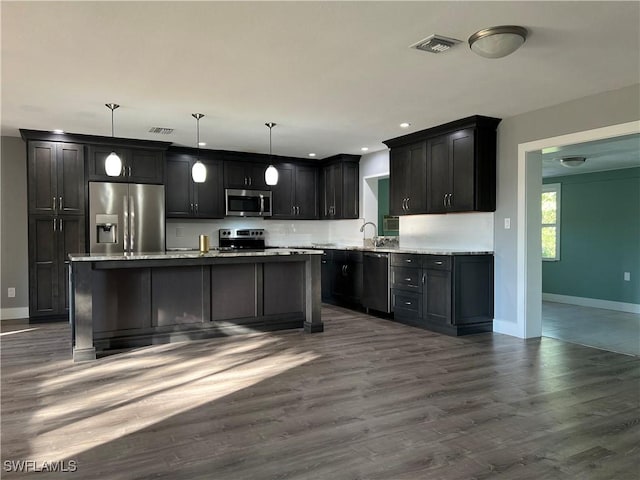 kitchen featuring dark wood-type flooring, appliances with stainless steel finishes, sink, and hanging light fixtures