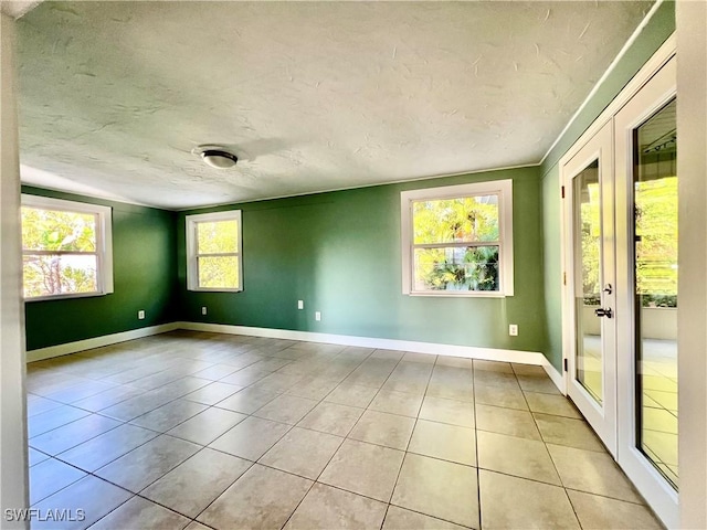 tiled spare room with a textured ceiling and french doors