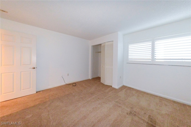 unfurnished bedroom featuring a closet and light colored carpet